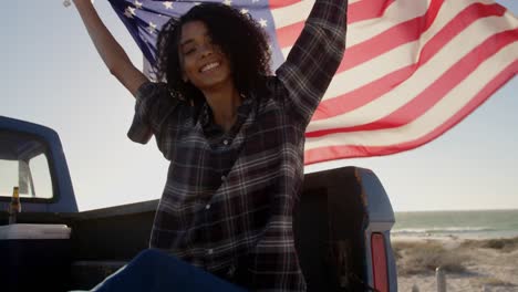 mujer sentada con una bandera estadounidense ondeando en una camioneta 4k