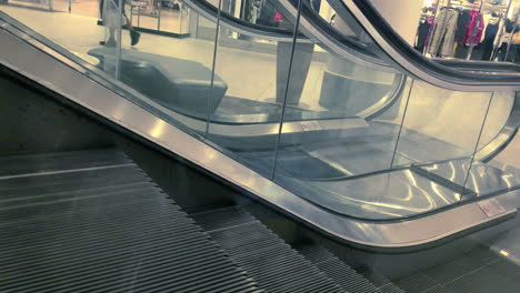 escalera mecánica en el centro comercial con gente montando en ella.