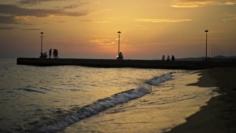 sunset over the sea with people on the pier