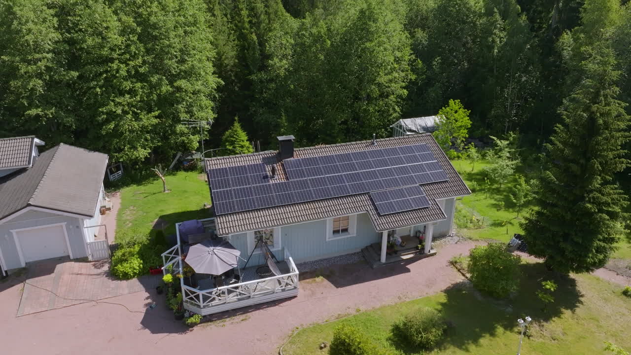 High angle drone shot of a house with solar cells on roof, green summer nature