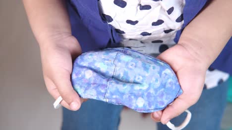 child holding a blue floral fabric mask