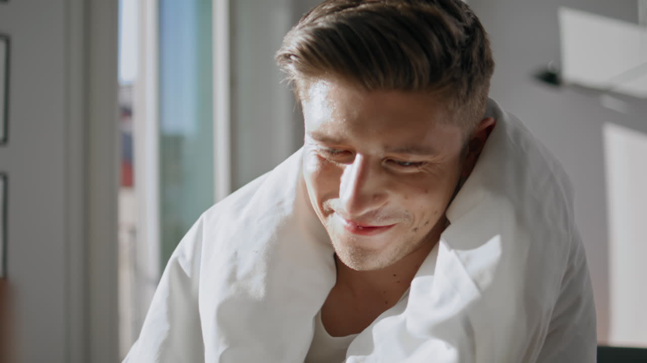 Portrait happy husband talking wife in morning sunlight. Cheerful man in blanket