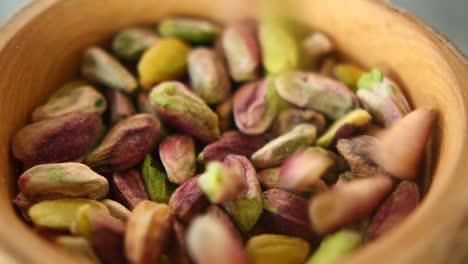 close up shot of pistachios in a wooden bowl