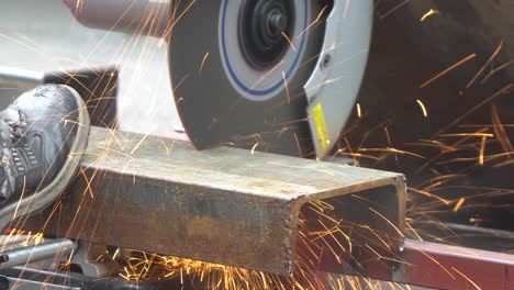 trabajador de la construcción cortando el marco del canal en forma de c de acero con el corte de la máquina de sierra circular macro de primer plano