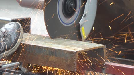 construction worker cutting steel c-shape channel frame with cutting circular saw machine close-up macro