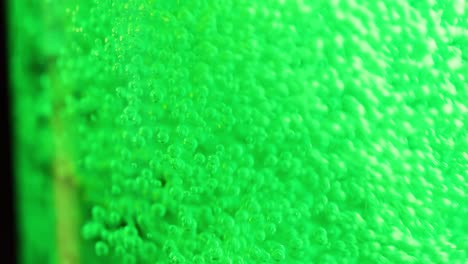 close-up view of green bubbles ascending in a vibrant liquid, showcasing dynamic movement and effervescence.