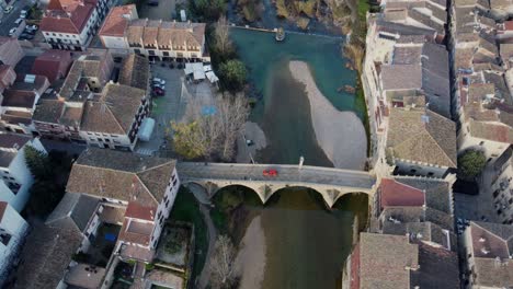 4k aerial drone shot of medieval arch bridge over blue river surrounded by historic village in spain