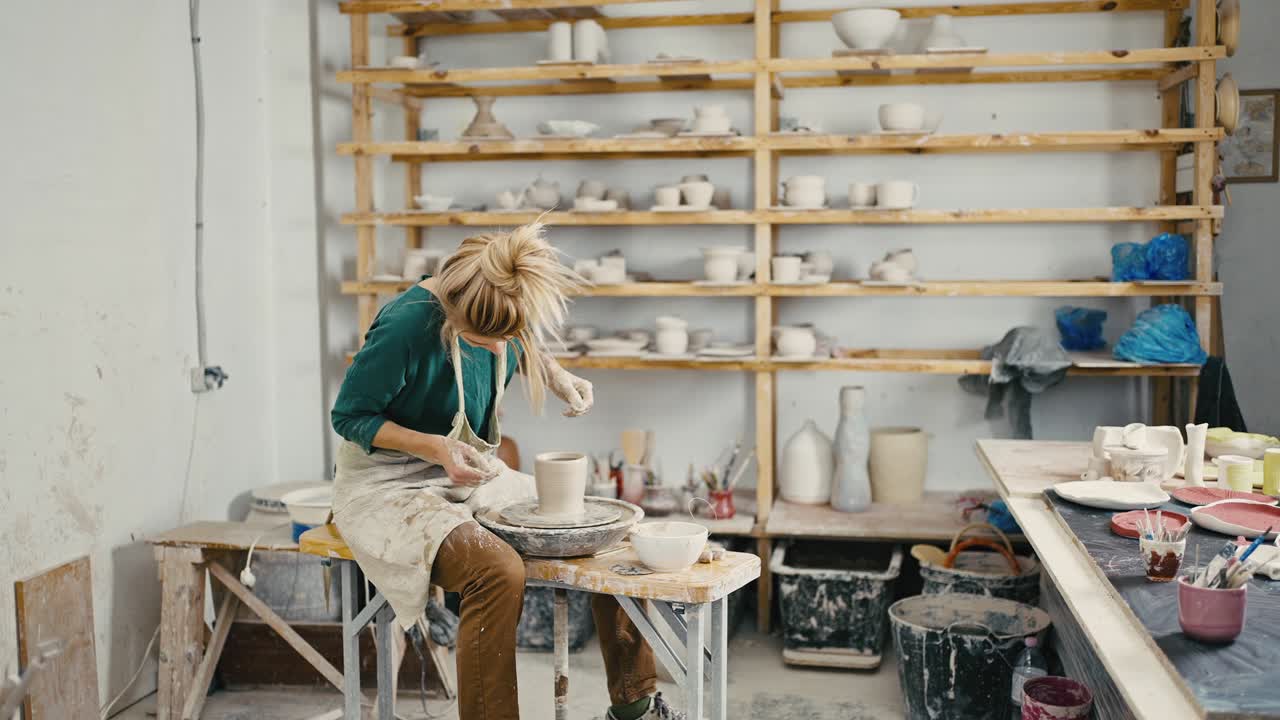 Female potter creating ceramic vase at studio, working on pottery wheel, tracking shot, slow motion
