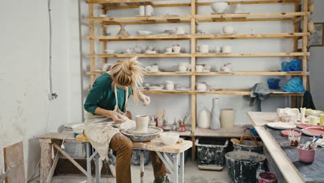 alfarera femenina creando un jarrón de cerámica en el estudio, trabajando en la rueda de cerámica, disparo de seguimiento, cámara lenta