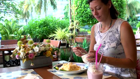 woman in a restaurant and pours a sharp sauce with chili on fried rice with vegetables and seafood