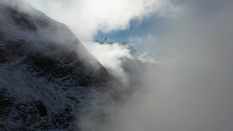 cinematic drone footage flying through the clouds in the swiss alps in switzerland with snow on the peaks