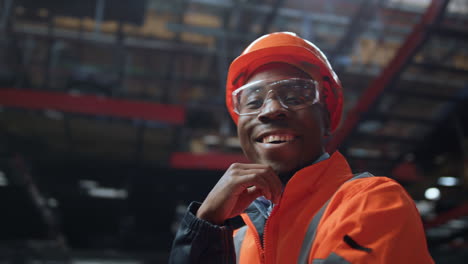 Joyful-supervisor-looking-camera-at-huge-industrial-special-production-warehouse