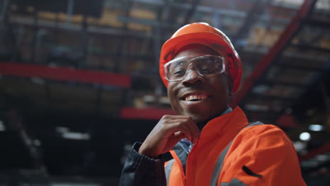joyful supervisor looking camera at huge industrial special production warehouse