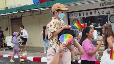 child on father's shoulders at pride parade