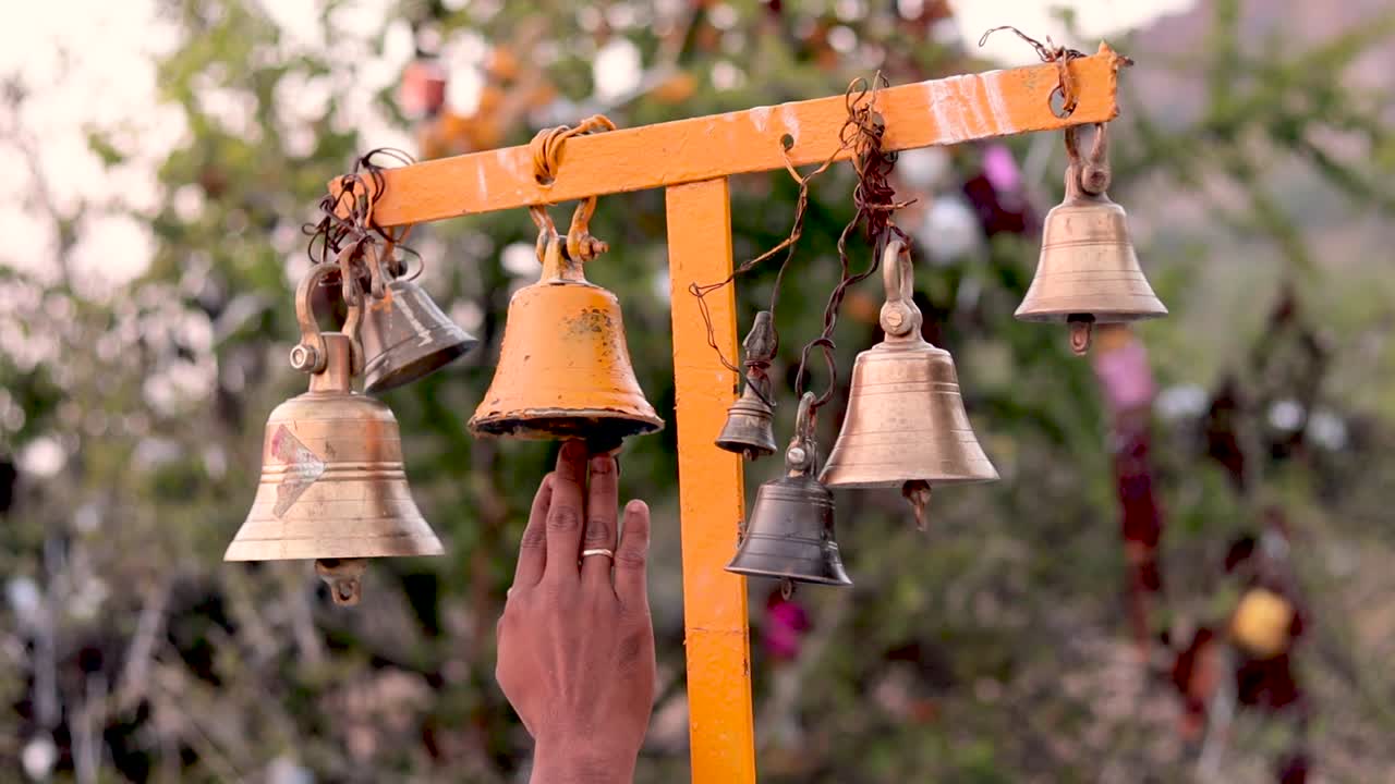Primo piano di una mano che suona la campana appesa fuori dal tempio