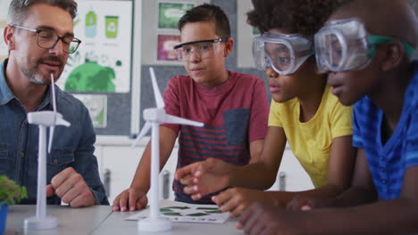 Diverse male teacher and children, learning about wind power and renewable sources of energy