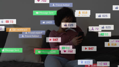 Animation-Von-Zahlen,-Symbolen-Und-Texten-In-Der-Nachrichtenleiste,-Lächelnde-Frau-Mit-Gemischter-Abstammung,-Die-Zu-Hause-Ein-Mobiltelefon-Benutzt