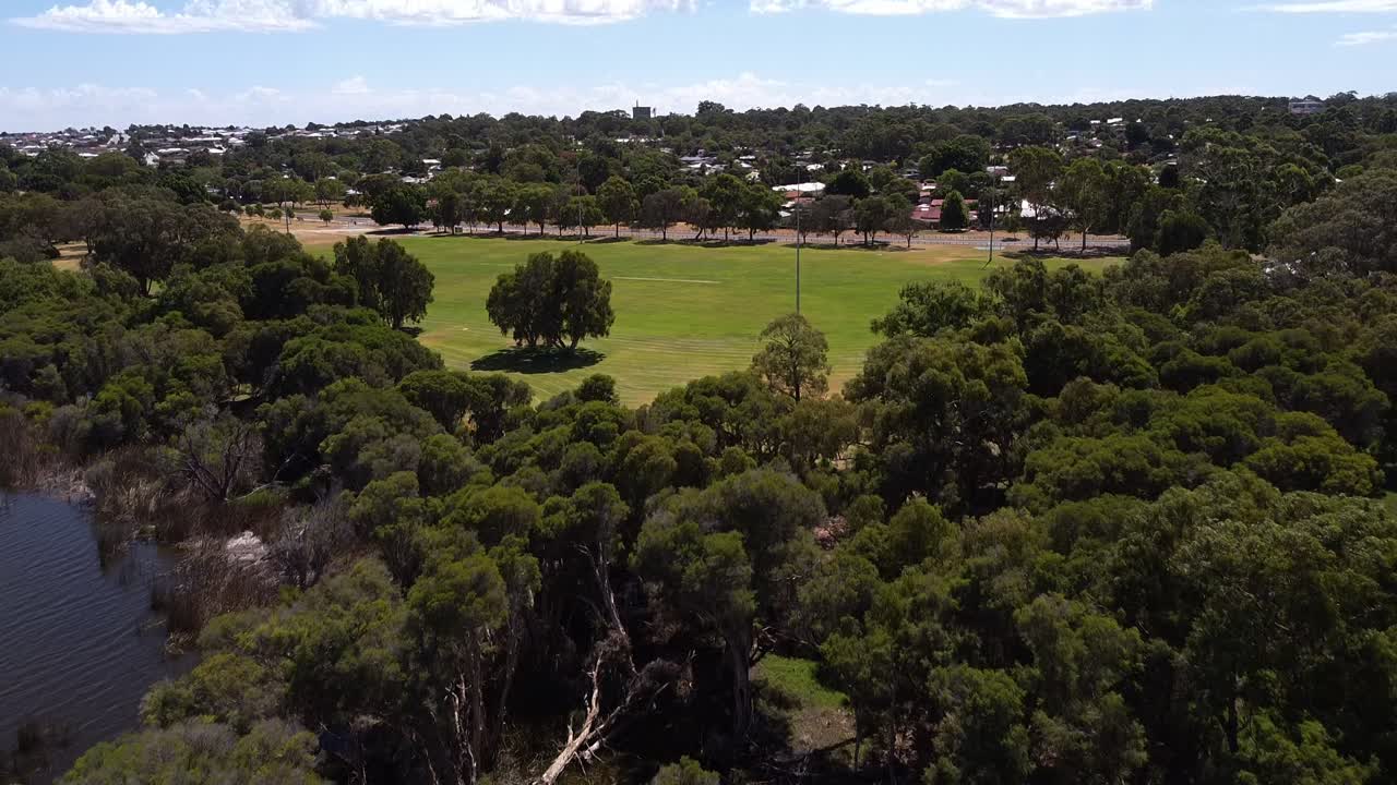 vista aérea sobre un parque verde con árboles que bordean la orilla del lago cerca de joondalup, perth