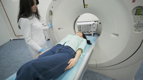 female patient is undergoing ct or mri scan under supervision of a radiologist in modern medical clinic. patient lying on a ct or mri scan bed, moving inside the machine.