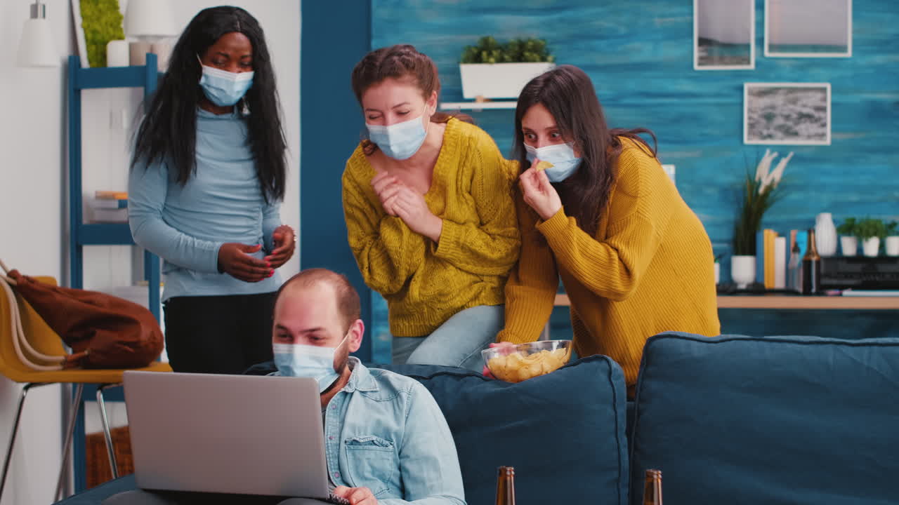 Man with protective masks holding laptop looking at comedy movie