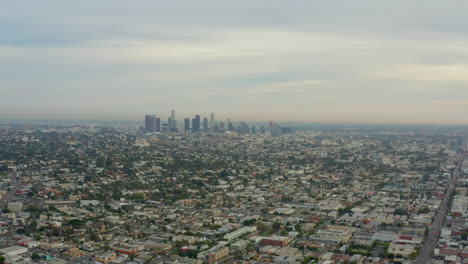 AERIAL:-Flight-over-Los-Angeles,-California-with-Skyline-in-background,-Cloudy-in-Daylight,