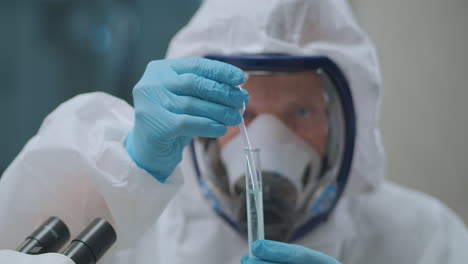 microbiólogo está tomando líquido con bacterias peligrosas de tubo de ensayo por pipeta en el laboratorio trabajando con productos químicos y toxinas fotografía de cerca de la cara y las manos humanas