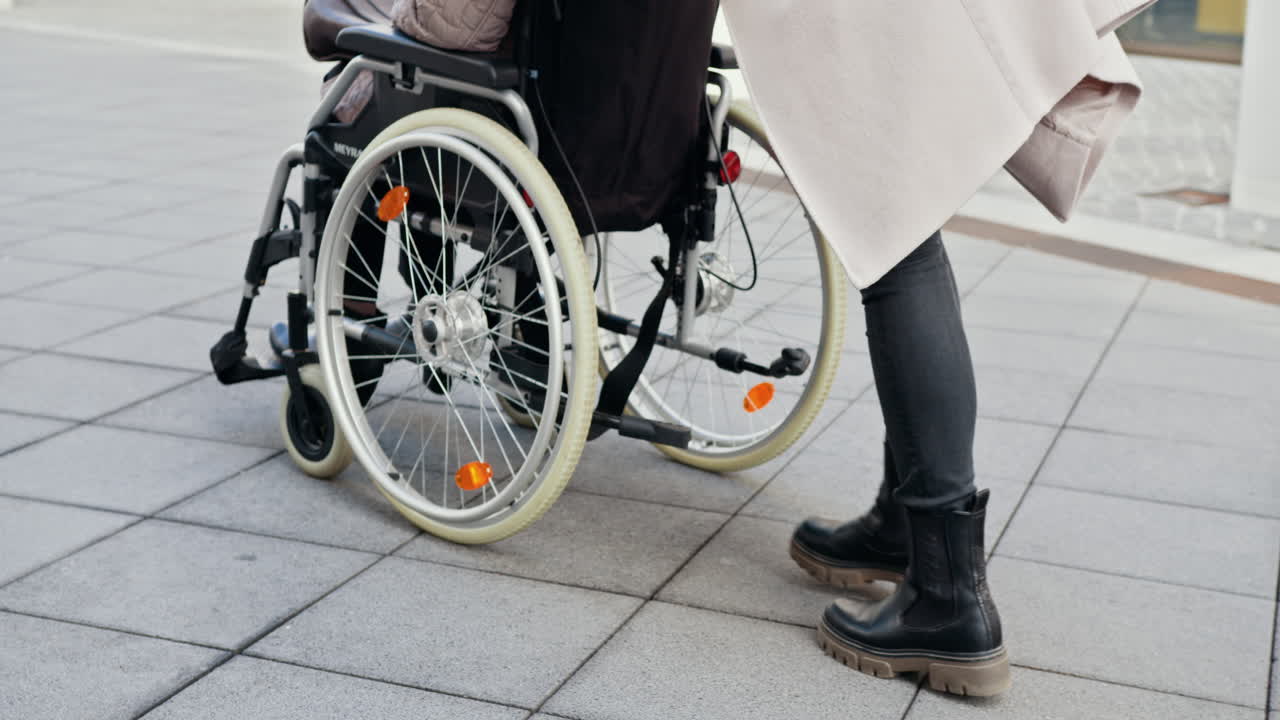 Woman assisting elderly person in wheelchair outside.