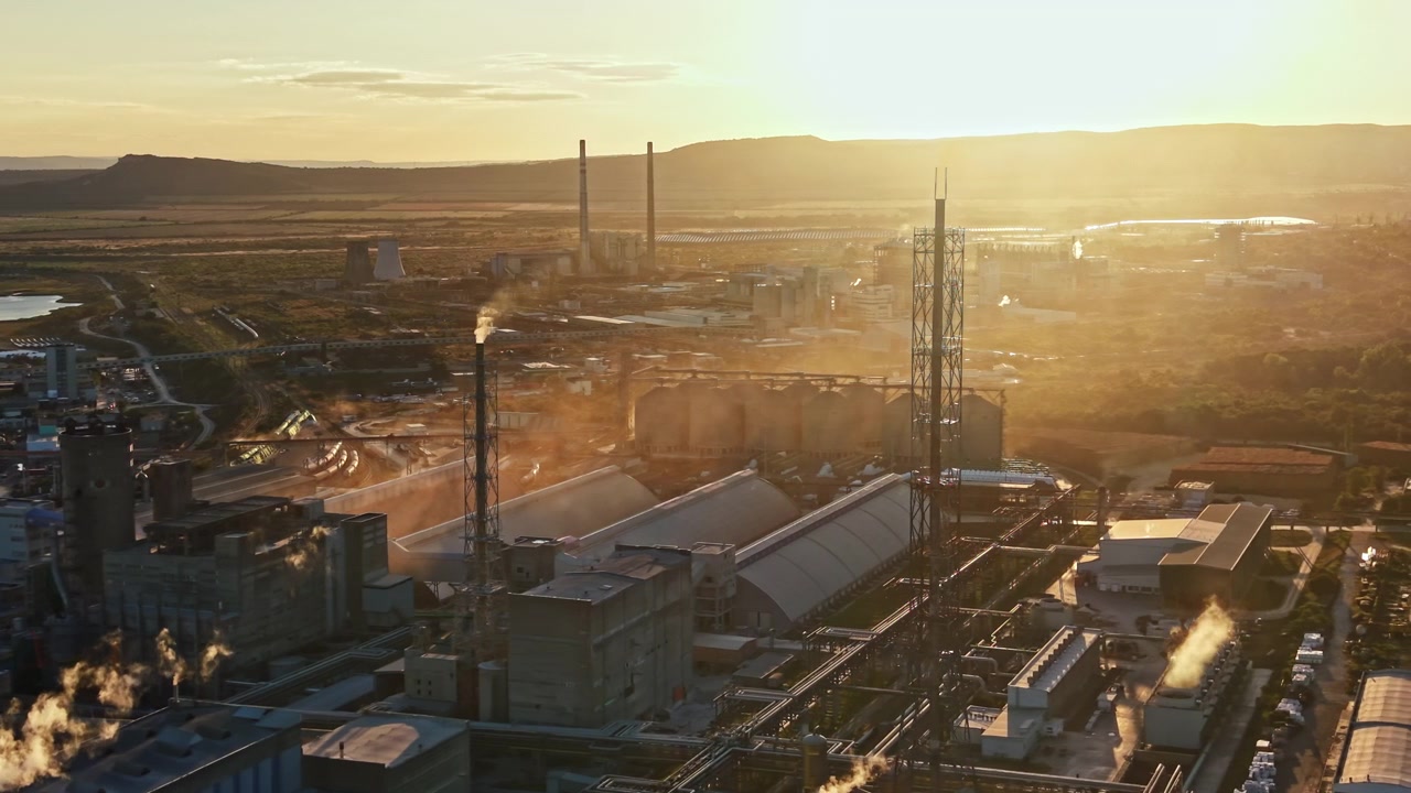 Industrial site during sunset with smokestacks and machinery in view