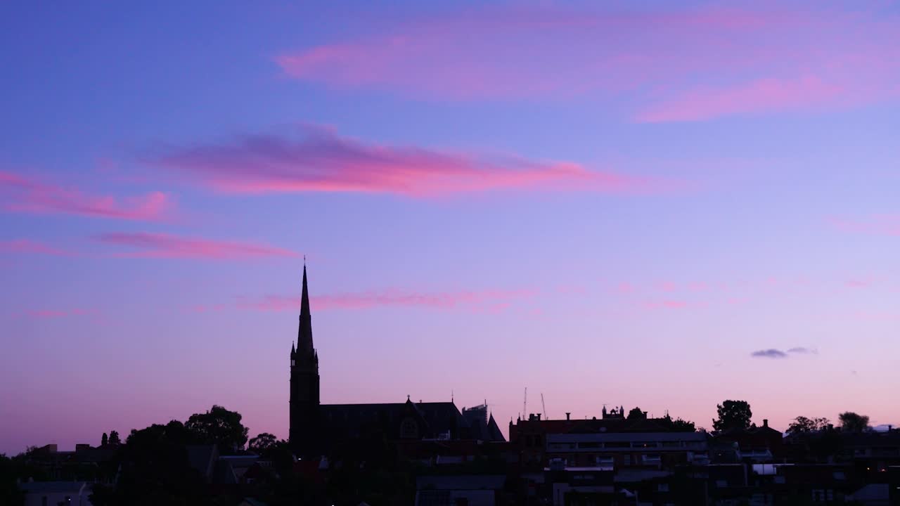 A stunning pink sunset falls behind a church.