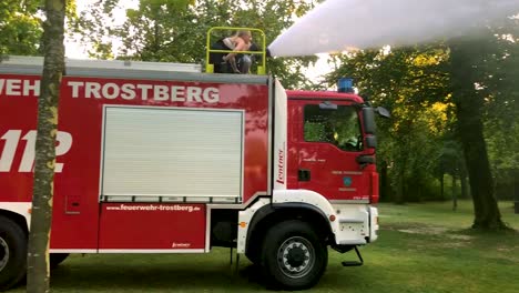 german firetruck spraying water for kids and trees on a hot summer day