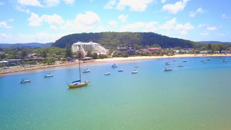 Amazing-blue-water-white-sands-beach-and-waterfront-houses-aerial-shot-on-a-hot-calm-sunny-day,-Ettalong,-Sydney-Australia