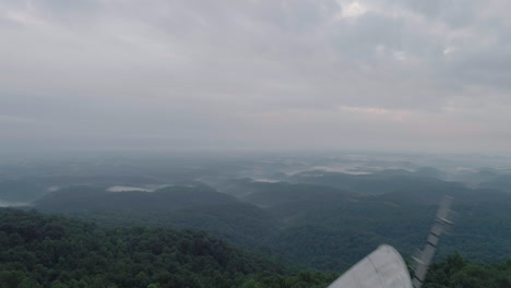 drone flying overhead of cell phone tower with two men on top in rural tennessee hills