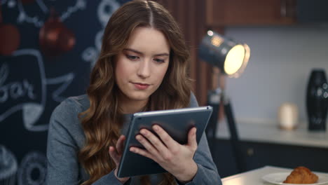 Portrait-of-focused-business-woman-using-tablet-computer-at-home-office.