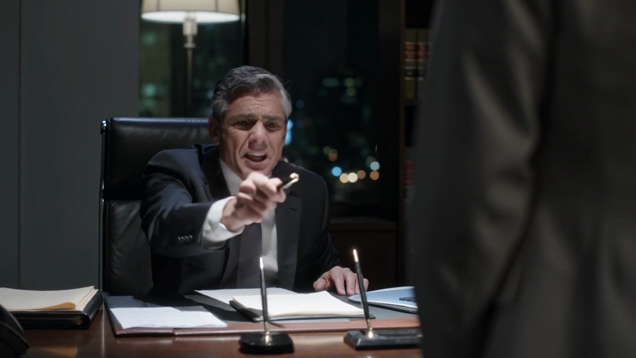 Extending pen, boss in dark suit seeking signoff after reviewing papers in night office