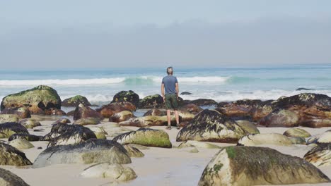 Rückansicht-Eines-älteren-Wanderers,-Der-Mit-Weit-Geöffneten-Armen-Am-Strand-Steht.