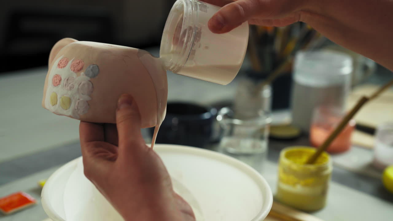 A Person is Pouring a Liquid Glaze Over a Ceramic Cup - Close Up