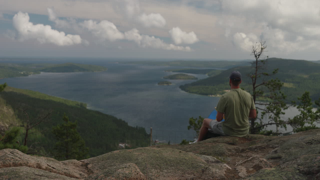 높은 해안을 바라보며 스웨덴 국기에 등을 대고 앉아 있는 남자