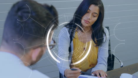 Animation-of-round-scanner-against-diverse-man-and-woman-discussing-over-a-document-at-office