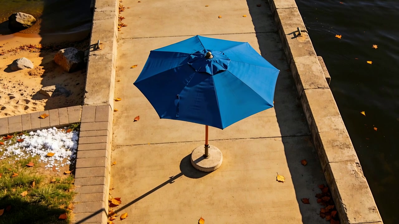 Roterende blå parasol drejer langsomt på betonsti, hvor brisen får udluftningen til at flagre.