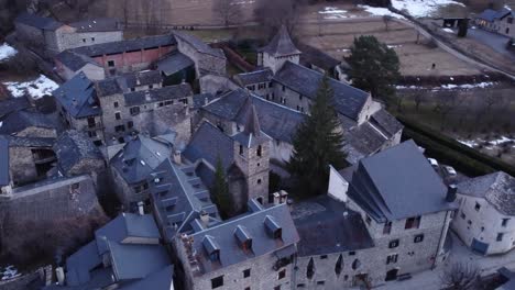 aerial of anciles, showcasing the rustic charm of an old town church and stone houses nestled in the aragonese pyrenees, spain