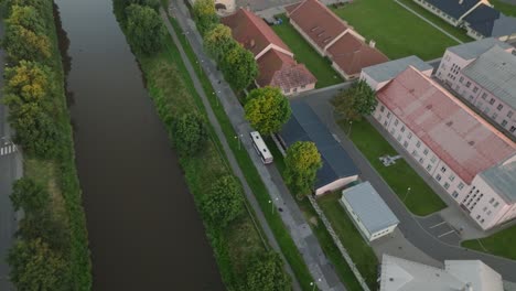 bus drives along a road with an avenue of trees around the river