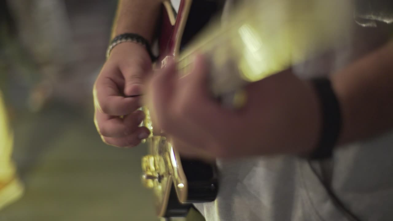 Un uomo che suona una chitarra elettrica a teatro, inquadratura fissa, primo piano, inserto
