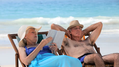 aged couple relaxing on beach chairs