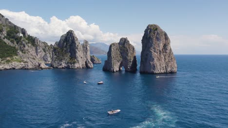 Boats-Exploring-the-Sea-Stack-Rock-Formations-of-Faraglioni,-Capri,-Italy