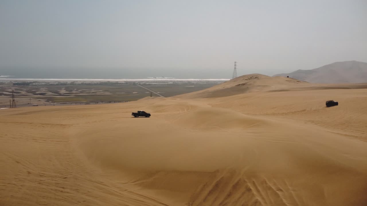 vista aérea alrededor de camiones que conducen sobre dunas en nublado ica, lima, perú - dando vueltas, disparo de drones