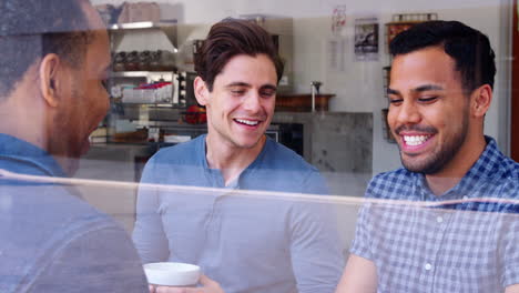 three male friends having coffee together at a coffee shop