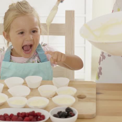 Niña-Riendo-Mientras-La-Masa-Se-Vierte-En-Moldes-Para-Muffins