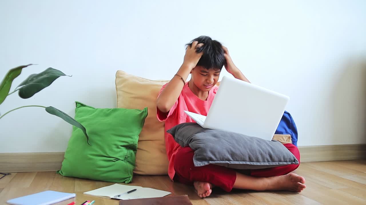 Frustrated young asian student struggles with online learning while homework on laptop