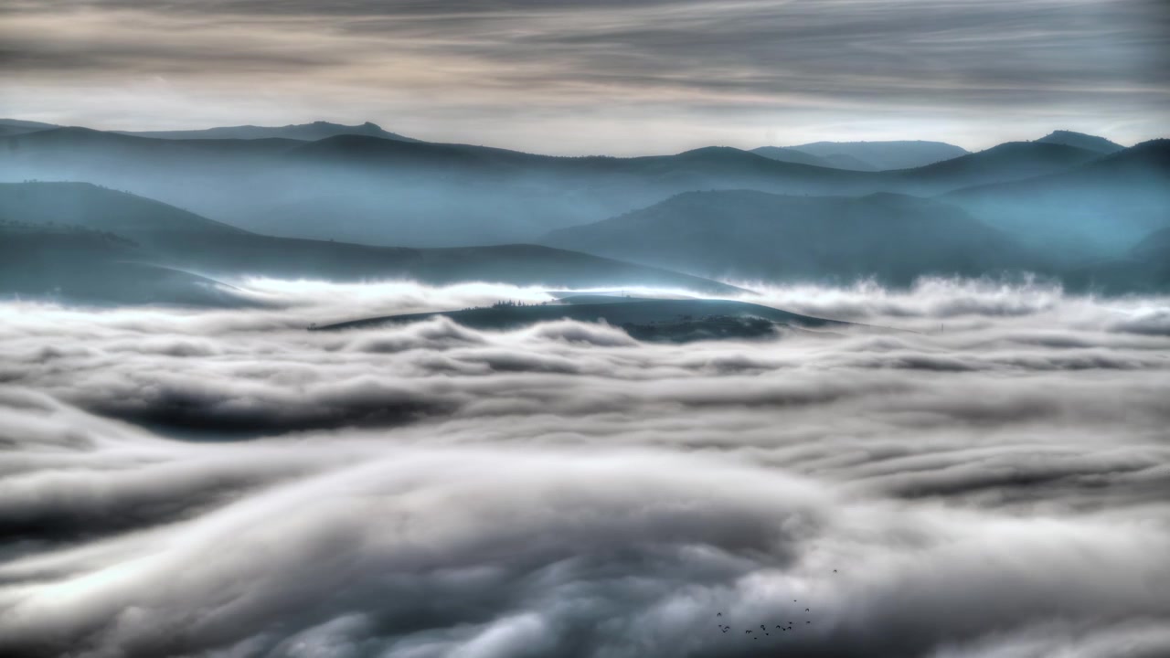 Denso mare di nuvole che avvolge un paesaggio montano.