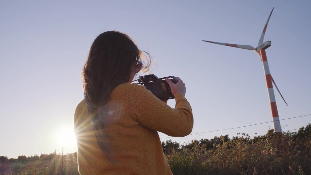 Filmmaker woman filming wind turbines